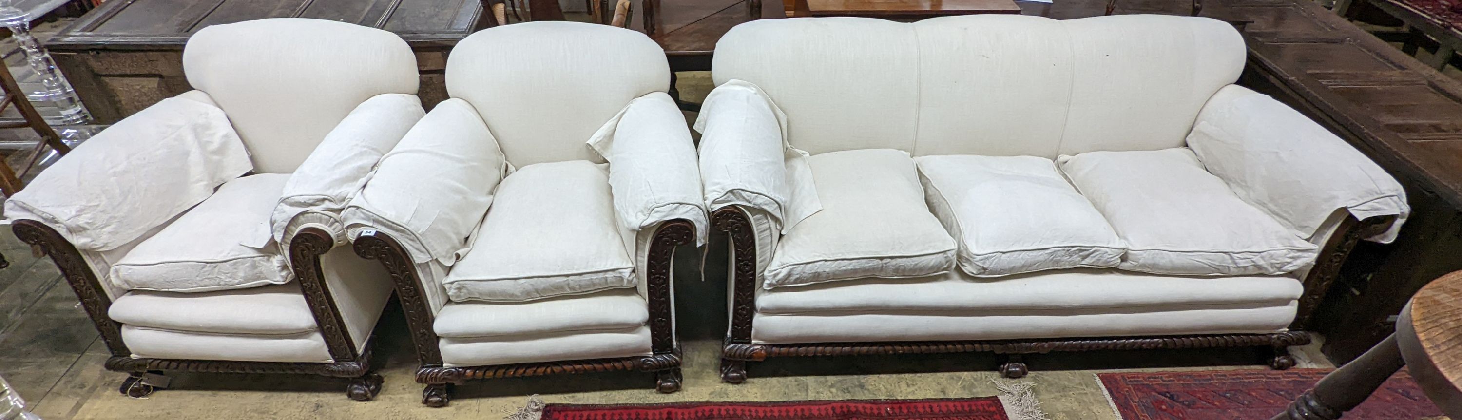 An early 20th century carved mahogany upholstered three piece lounge suite on claw and ball feet, the settee length 194cm, depth 80cm, height 80cm